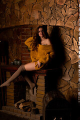 Beautiful girl sitting next to the fireplace. Luxury interior decorated for Christmas with fir branches and toys