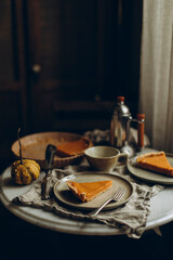 two servings of pumpkin pie on a plate with a dessert fork. a piece of pumpkin cheesecake on a white marble round table