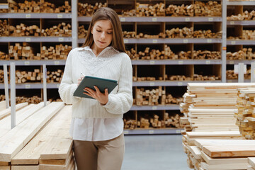 Woman with tablet in a timber and lumber warehouse. Product acceptance and quality control