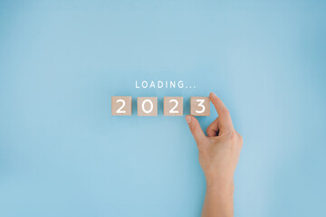 Female hand putting wooden cube for countdown to 2022. Loading year from 2022 to 2023. New year start concept