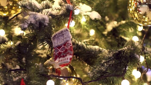 A New Year's knitted glove hanging on a branch of a Christmas tree