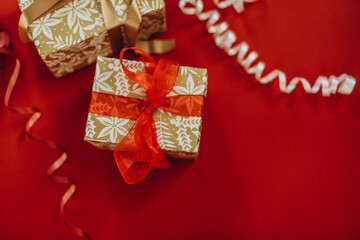 two gift boxes on a red background. christmas gifts decorated with beige and red ribbon.