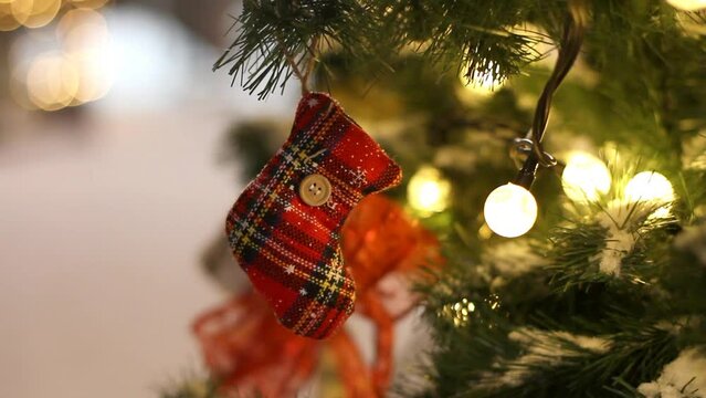 A New Year's plaid sock with a button hanging on a branch of a Christmas tree