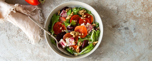 bowl with salad with baked beetroot, persimmon and feta cheese on the table