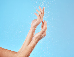 Hand, water and cleansing for health, wellness and bodycare on a blue studio background. Hands,...