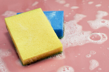 soap foam and two sponges on a pink background