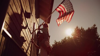 Proud Patriotic Dad Holding His Young Daughter of His Shoulders, Helping Her to Put the United States of America Flag on the Wall of Their House to Celebrate a National Holiday. Sunny Day in USA. - Powered by Adobe