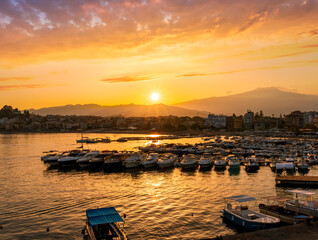 picturesque sunrise or sunset in a sea port with a gulf dock pier with tour boats and a town with cloudy sky on background of a seashore landscape