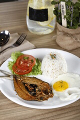 Filipino breakfast of fried bangus (milkfish) with garlic flakes and egg, lettuce, tomato and garlic fried rice