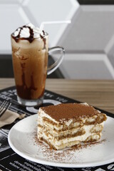 Square slice of tiramisu with dark choco frappe