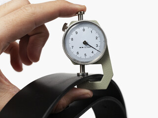 Measuring with a thickness gauge of a leather billet. Isolated in a white background.