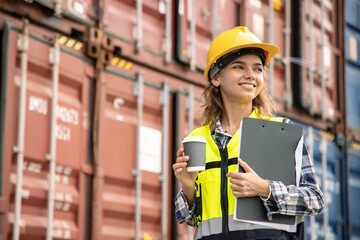 Female engineer happily working with coffee at an international cargo yard. Inspection for or...