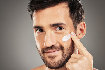Portrait, skincare and man with face cream in studio for moisturizing on gray background mockup....