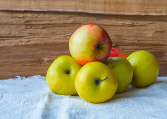 Apples lying on a white tablecloth. Still life with apples on a wood background.