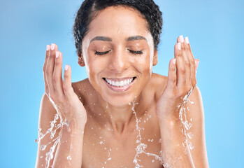 Water splash black woman cleaning face on blue background for health, beauty and skin care morning...
