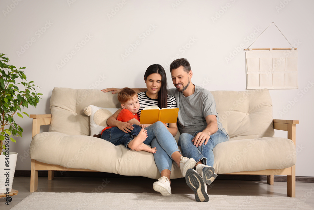 Sticker Happy family reading book together on sofa in living room at home