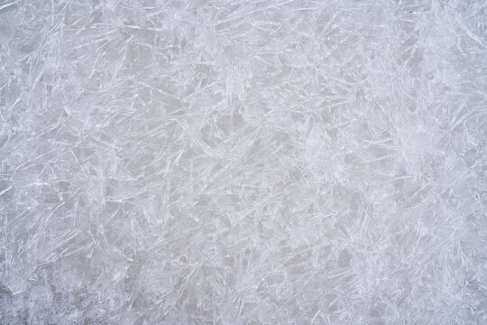 Fresh ice surface texture. Winter background with frozen snowflakes and snow mounds.