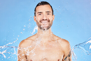 Fototapeta na wymiar Skincare, portrait and water splash of man in studio isolated on a blue background. Health, cleaning and male model from Canada bathing and washing for wellness, body care and fresh beauty routine.