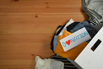 Carton boxes with clothes on wooden table. Charity, donation and reuse recycle concept