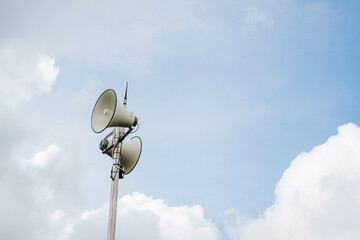 White megaphones mounted on poles in outdoor against blue sky background