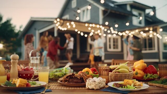 Backyard Dinner Table with Tasty Grilled Barbecue Meat, Fresh Vegetables and Salads. Happy Joyful People Dancing to Music, Celebrating and Having Fun in the Background on House Porch.