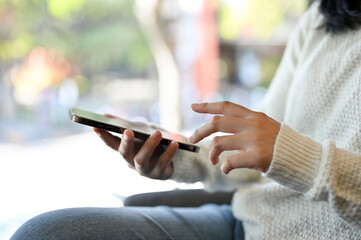 An Asian woman using her smartphone while relaxing in the cafe. rear view
