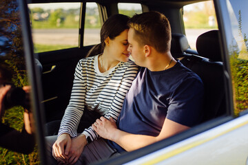 Smiling young couple inside a car. Kissing in the car