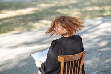 girl in the park with a book. red hair.
