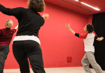 Physical theater teacher indicates movement to two students who imitate him