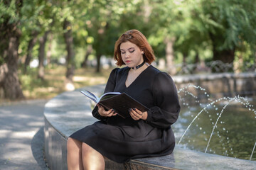girl reads a book in the park outdoors.