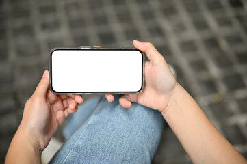 A female using her smartphone. mobile phone white screen mockup in a horizontal position