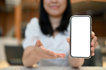 Asian woman showing a smartphone white screen mockup to camera. cropped image