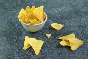 White bowl with corn chips nachos on the black concrete background. Mexican chips nachos.