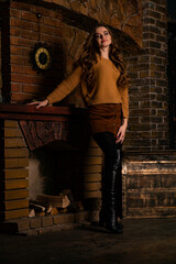 A young girl sitting in a chair near a fireplace looking determined