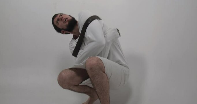 Violent psychiatric patient. Young caucasian man  with beard  and insane smile sitting on floor trying to free from straitjacket in  asulym. Treatment of schizophrenia in psychiatric clinic