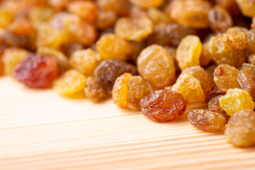 Close up shot of raisins on wooden table. Fresh tasty raisins on light wooden background