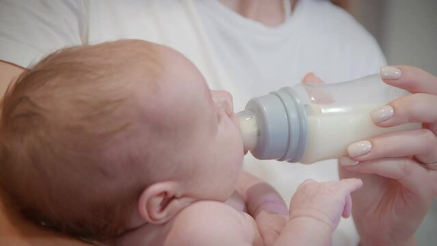 Mother feeds the baby from a bottle with a pacifier.