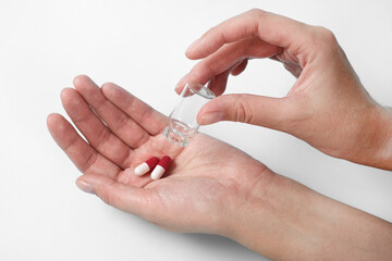 hand holds a glass transparent jar with pills on a light background close-up