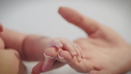 The hand of a small newborn baby touches the mother's hand.