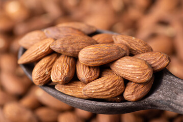 Big nuts of almond in dark wooden spoon. Close up photo of tasty almonds
