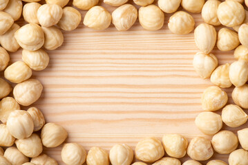 Hazelnuts frame background. Frame made of peeled off hazelnuts on wooden table