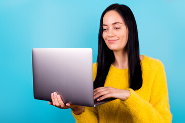 Naklejka premium Photo of young adorable pretty girlish woman confident professional programmer wear yellow sweater hold computer typing isolated on blue color background.
