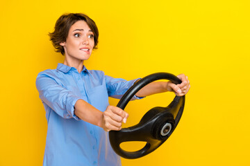 Photo of funny scared girl dressed blue shirt riding auto looking empty space isolated yellow color...