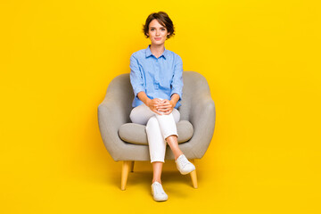 Full length photo of serious confident girl dressed blue having rest sofa isolated yellow color background