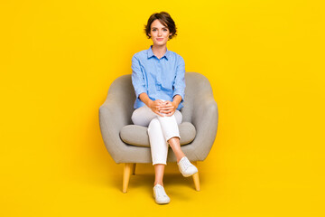 Full length photo of serious confident girl dressed blue having rest sofa isolated yellow color...