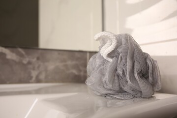 Fototapeta na wymiar Grey shower puff on washbasin in bathroom, closeup. Space for text