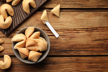 Tasty fortune cookies and paper with prediction on wooden table, flat lay. Space for text