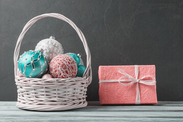 Basket with Christmas balls and pink gift box. Christmas and New Year card