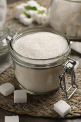 Jar of white sugar on wicker mat, closeup