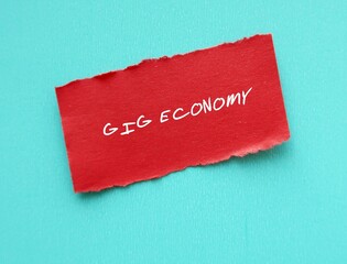 Red torn paper on blue background with handwritten text GIG ECONOMY where people earn income...